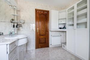 Un baño con lavabo y puerta de madera. en El Jardín de Estrella, en Navacerrada