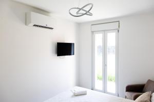 a white living room with a tv and a couch at Residenza Elsa in Domodossola