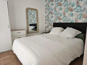 Un dormitorio con una gran cama blanca y un espejo. en Les campagnettes, en Voulangis