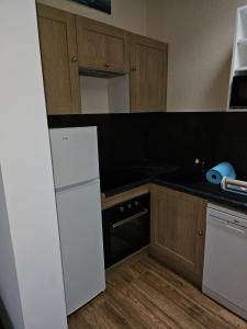 Una cocina con refrigerador blanco y gabinetes de madera. en Les campagnettes, en Voulangis
