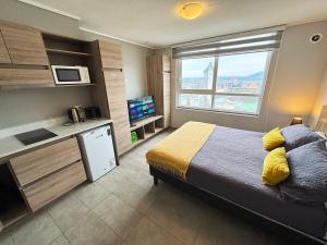 a bedroom with a bed and a kitchen with a window at Apart Hotel Bauerle & Apartamentos in Temuco