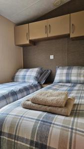 two beds sitting next to each other in a room at The Lake District Caravan in Lamplugh