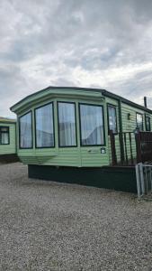 a green mobile home sitting on top of gravel at The Lake District Caravan in Lamplugh
