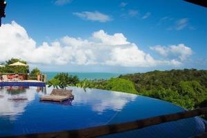 a swimming pool with a view of the ocean at Villas Supreme Apartamentos in Maceió