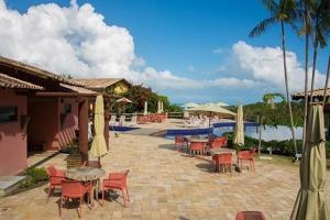 a patio with tables and chairs next to a pool at Villas Supreme Apartamentos in Maceió