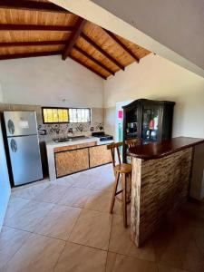 a large kitchen with a refrigerator and a counter at Condominio Portal del Sol, Cabaña en la Mesa de los Santos in Los Santos