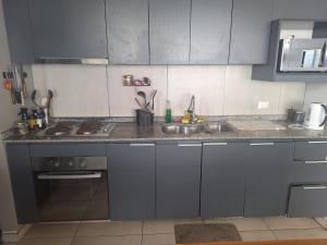 een keuken met grijze kasten en een wastafel bij Dpto 2 piezas 2 baños al lado de las dunas de Concon in Viña del Mar