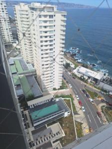 een uitzicht op een gebouw en de oceaan vanaf een wolkenkrabber bij Dpto 2 piezas 2 baños al lado de las dunas de Concon in Viña del Mar +1 foto