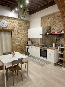 a kitchen with white cabinets and a table with chairs at La Casina del Corso in Massa Marittima