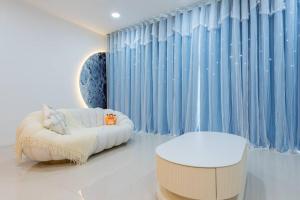 a living room with a couch and a stool and blue curtains at Emerald Hill Kuala Lumpur by HLG in Kuala Lumpur