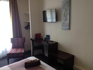 a hotel room with a bed and a desk and a chair at Hotel de la Paix in Caen