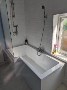 una vasca bianca in un bagno con finestra di Beach Walk Cottage a Walton-on-the-Naze