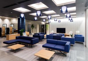 una sala de espera con sofás azules y TV en Daiwa Roynet Hotel Tokushima Ekimae en Tokushima