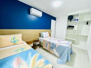 a bedroom with two beds and a blue wall at Apartamento dos Sonhos na Praia dos Anjos in Arraial do Cabo