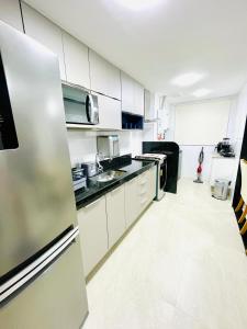a kitchen with white cabinets and a stainless steel refrigerator at Apartamento dos Sonhos na Praia dos Anjos in Arraial do Cabo
