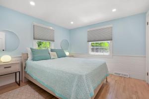 a blue bedroom with a bed and two windows at 78 Bucks Creek Road Chatham - Saltaire in Chatham