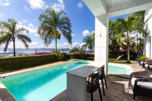 une piscine avec une table et des chaises et l'océan dans l'établissement Villa St Teresa do Porto: HarboursideVilla-SeaViews-Pool-BBQ-StarLink-6Bedrm, à Rio de Janeiro