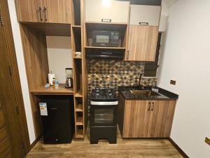 a small kitchen with a stove and a microwave at Departamento en Cochabamba con hermosa vista in Calacala