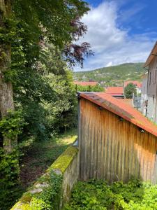 ein Holzzaun neben einem Gebäude mit Bäumen in der Unterkunft Appartement lac et montagne in Gérardmer