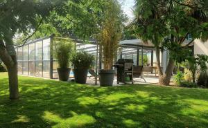 a greenhouse with a table and chairs in a yard at Fare-Kermenezy maison avec piscine chauffée in Locmaria-Grand-Champ