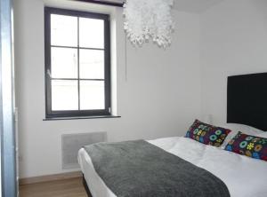 a bedroom with a bed and a window and a chandelier at Les Mini-lofts de Paul et Virginie in Wimereux