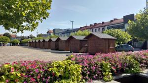 a row of wooden huts in a parking lot with flowers at THE ONE Apartment in Tomaszów Mazowiecki