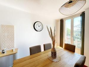 a dining room with a table and a clock on the wall at Somptueux appartement duplex proche RER in Villemomble