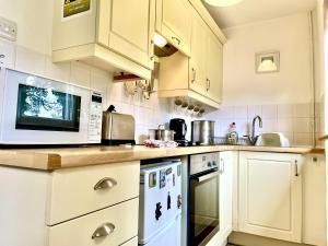 a kitchen with white cabinets and a microwave at 2 Bed Lodge - Sleeps 4 - Pets - Pool - Garden in Penzance +7 photos