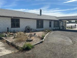an old white house with a wheel in front of it at JET Motor Inn in Powell