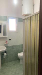 a bathroom with a toilet and a sink and a window at Cascina Vittorio, Relax in campagna con barbecue vicino Gallipoli in Noha