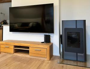 a flat screen tv sitting on a wall next to a wooden entertainment center at FeWo Herz im Allgäu in Lindenberg im Allgäu