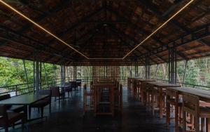 a restaurant with tables and chairs in a forest at Lakedale Resorts in Thekkumkara