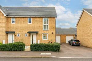 a brick house with a car parked in a parking lot at Stylish & Chic 3 bed House in Cambourne