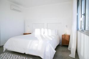 a white bedroom with a white bed and a window at La Posta Beach Hotel in Punta del Este