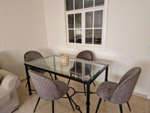 a glass dining room table with chairs and a window at Salusahome parking gratuito in Córdoba +8 photos