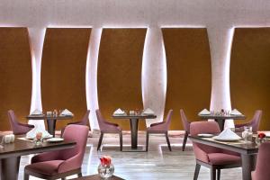 a dining room with tables and chairs and columns at Atana Hotel in Dubai