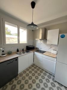 a kitchen with white cabinets and a white refrigerator at Les Balcons du Couloubret in Ax-les-Thermes +17 photos