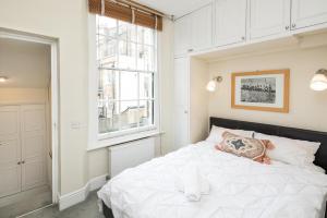 a bedroom with a white bed with a stuffed animal on it at High-ceiling Gorgerous Victorian flat with private garden - 3 mins to Hyde Park, Kensington Palace, 8 mins NottingHill, High Street Kensington station in London