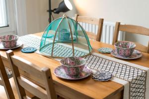 a table with cups and saucers on top of it at High-ceiling Gorgerous Victorian flat with private garden - 3 mins to Hyde Park, Kensington Palace, 8 mins NottingHill, High Street Kensington station in London