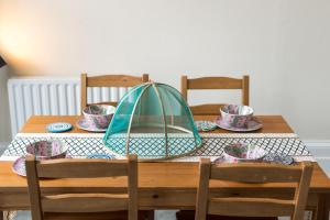 a wooden table with chairs and a table with hats on it at High-ceiling Gorgerous Victorian flat with private garden - 3 mins to Hyde Park, Kensington Palace, 8 mins NottingHill, High Street Kensington station in London +18 photos