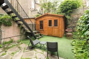 a patio with two chairs and a wooden shed at High-ceiling Gorgerous Victorian flat with private garden - 3 mins to Hyde Park, Kensington Palace, 8 mins NottingHill, High Street Kensington station in London