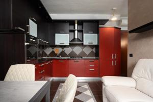 チニゼッロ・バルサモにあるClassbnb - Cozy apartment 15 minutes from Milanのキッチン(赤いキャビネット、白い椅子付)