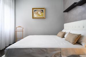 チニゼッロ・バルサモにあるClassbnb - Cozy apartment 15 minutes from Milanの壁に絵が描かれた部屋の白いベッド1台 +7枚の写真