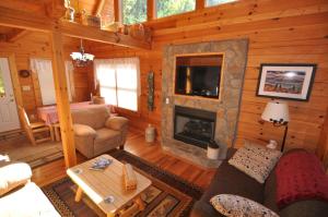 a living room with a fireplace in a log cabin at Cherokee Ridge Retreat in Whittier