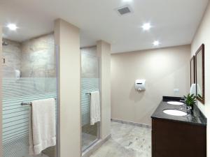 a bathroom with two sinks and a shower at Coconut Court Beach Hotel in Bridgetown