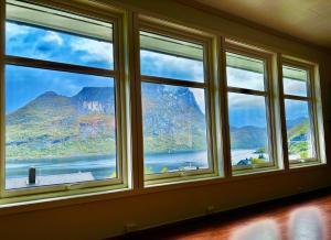 a room with three windows with a view of a mountain at Spacious Waterfront Gem - Panoramic View - Terrace in Fjordgård