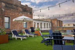 Un patio con sillas y mesas y una sombrilla. en Hotel Hardware, en Dayton