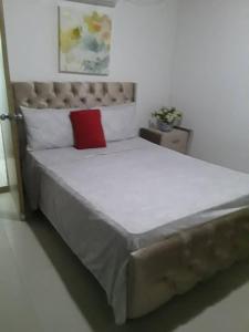une chambre avec un grand lit avec un oreiller rouge dans l'établissement Hostal altos de riomar Barranquilla inn, à Ciudad Jardín