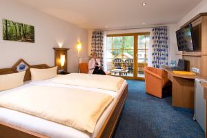a hotel room with a bed and a woman in a room at Silberkönig Schwarzwald Hotel & Restaurant Ringhotel in Gutach im Breisgau