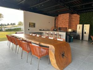 un grande tavolo di legno con sedie e una cucina di IPÊ GARDEN 10 Suites Piscina Churrasqueira a Boituva